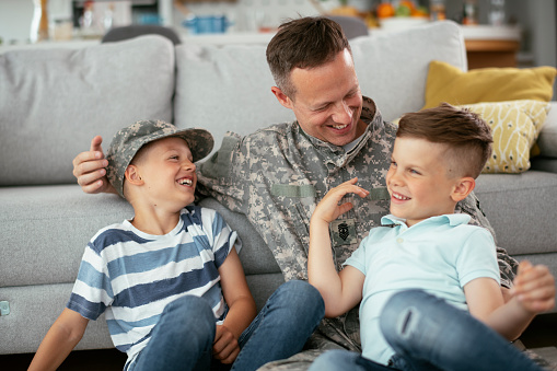 Happy soldier sitting on the floor with his family. Soldier enjoying at home with children.