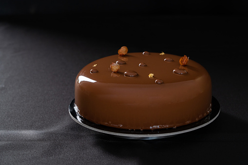 Chocolate glossy birthday cake isolated on a black background. Copy space. Close up. High quality photo
