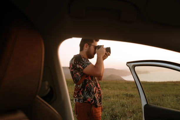 istock Young man using a DSLR camera in a beautiful area at sunset 1272409459
