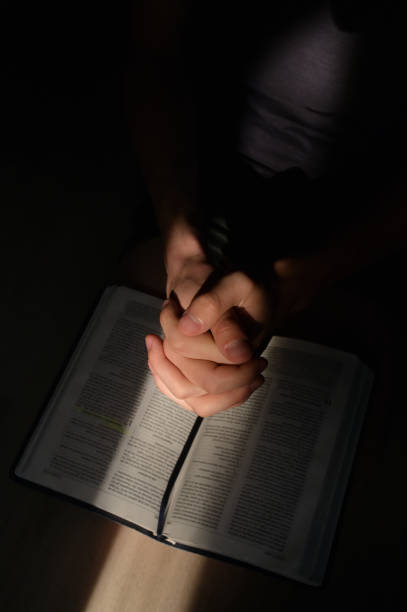 istock Closeup young man praying hands clasped and Sunrays 1272409952