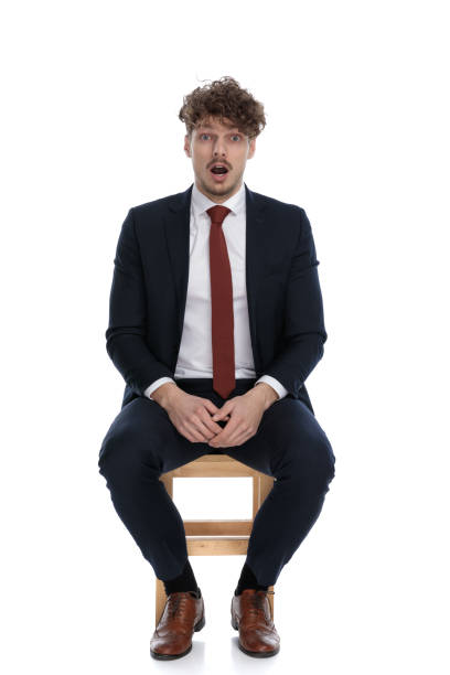 istock handsome surprised businessman sitting with his hands on his lap 1272411337