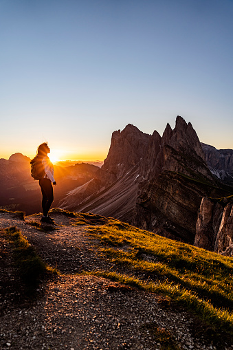 Female hiker watching sunset on top of the mountain peak of South Tirol with a great view.