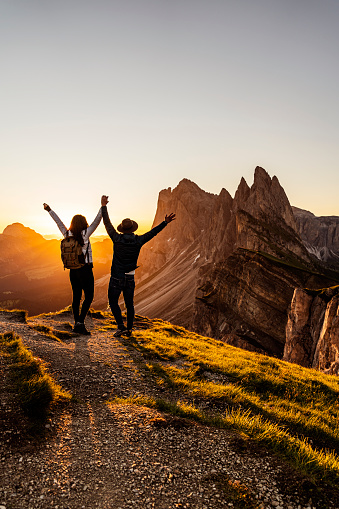 Two happy tourists backpackers greetings sunrise or at mountains top of South Tirol with a great view by sunset.