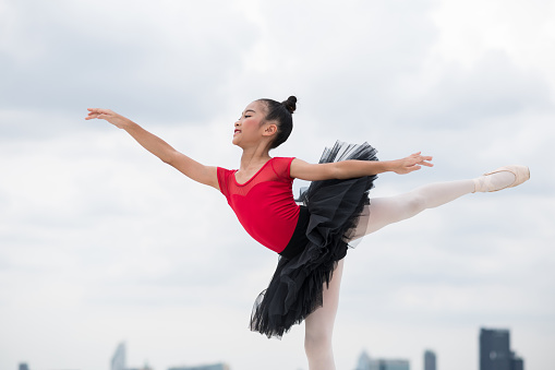 Asian ballerina girl dancing on the rooftop of the building city background.