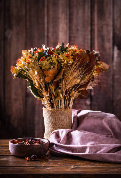 Bouquet of dried autumn flowers on a rustic wooden table and background