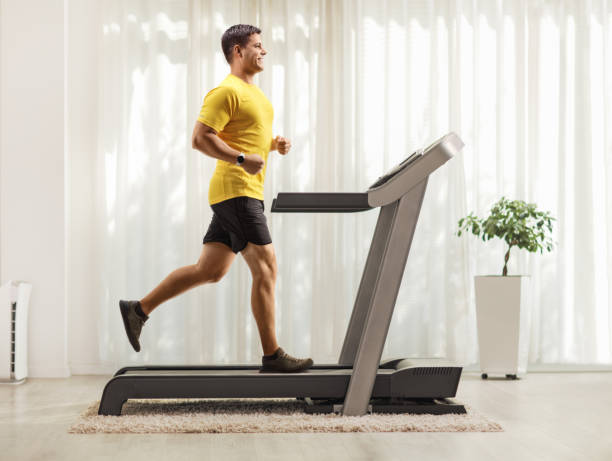 istock Smiling young man running on a treadmill at home 1272415894