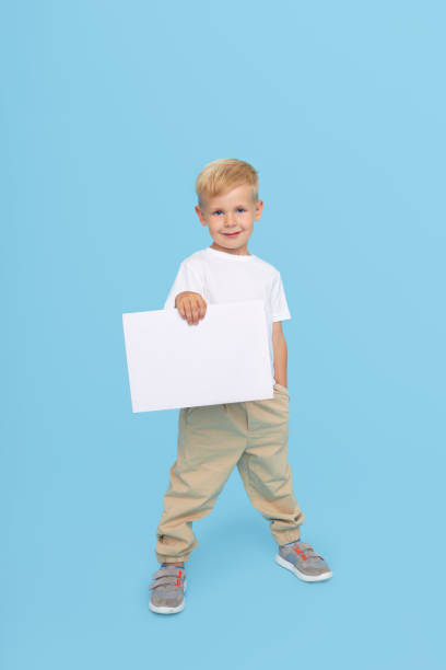 istock A cute laughing child boy is holding a white signboard with an empty space for text. Advertising of childrens products and the announcement of discounts and sales 1272417294