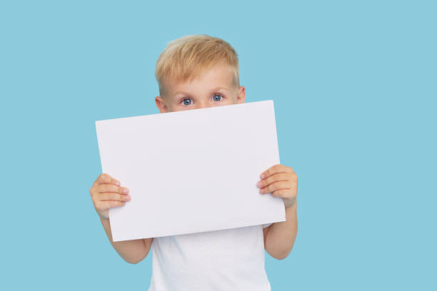 istock A cute laughing child boy is holding a white signboard with an empty space for text. Advertising of childrens products and the announcement of discounts and sales 1272417313