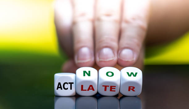 Hand turns dice and changes the expression "act later" to "act now". Hand turns dice and changes the expression "act later" to "act now". climate crisis photos stock pictures, royalty-free photos & images