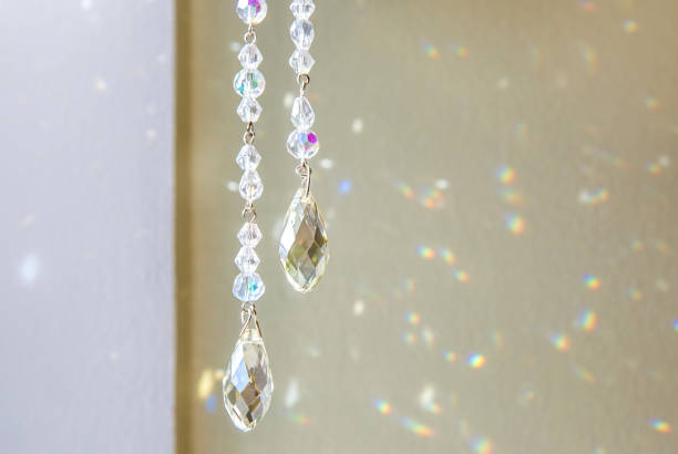 Selective focus on tear drop shape crystal rainbow maker suncatcher hanging in home. Good Feng Shui, Sha Chi energy flow concept.