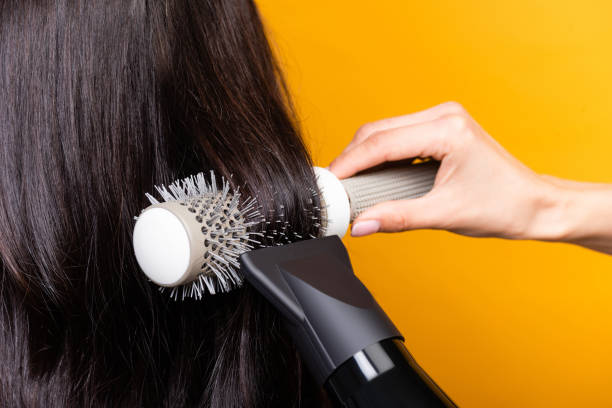 cropped view of hairdresser using hairdryer and brush isolated on yellow - hair care hairbrush hair dryer human hair imagens e fotografias de stock