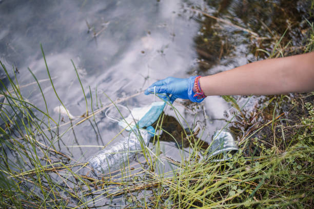 istock Ecology Responsible Person Is Taking Protective Face Mask Leftover In The Nature After Being Used From People 1272421977