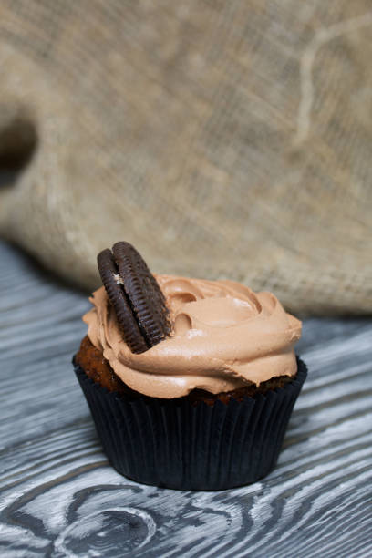 istock Chocolate cupcake with cream cheese cream. On pine planks painted black and white. 1272422685