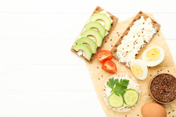 istock Crispbread with cream cheese, eggs and vegetables on white wooden table 1272423755
