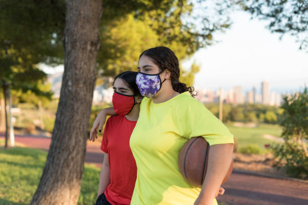 젊은 남자와 여자는 농구와 보호 마스크를 가지고 코트로 걸어. - basketball teenager nature outdoors 뉴스 사진 이미지