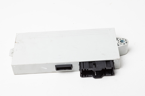Plastic control unit of a car engine with black elements on a white isolated background - the connecting center of various subsystems, components and assemblies. A spare part for a catalog for sale.