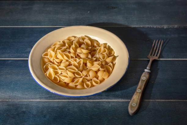 istock Pasta shells on blue background, closeup view. Cooking italian cuisine concept 1272430846