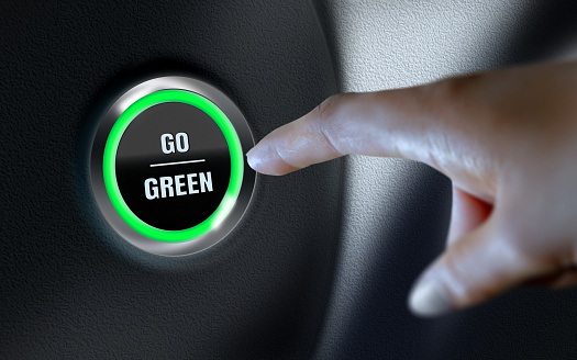 Go Green title written over car start button on leather dashboard. Business, finance, technology and money concepts over futuristic electronic circuit. High resolution image is designed to crop all your social media, blog or print needs. Produced with Photoshop and 3D software.