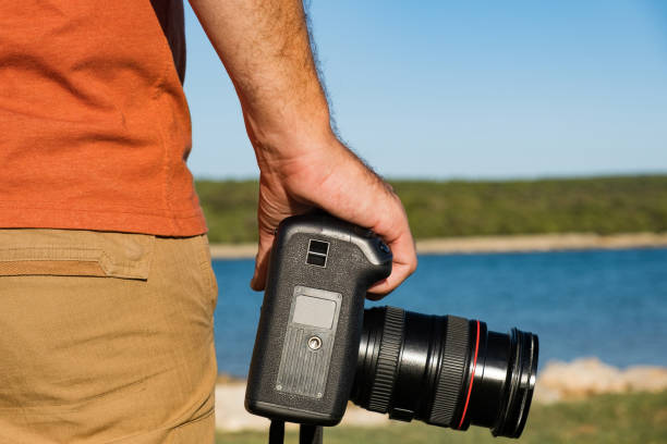 istock Anonymous man holding DSLR camera in hands next to seashore 1272436773
