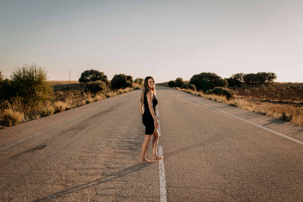 Una donna con un vestito nero su una strada vuota - foto stock