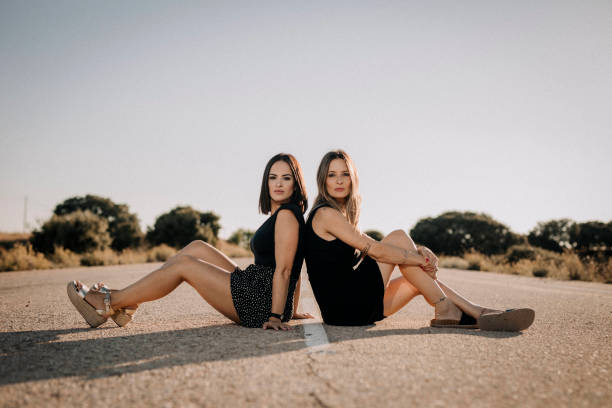 Two beautiful women sitting on a road - fotografia de stock