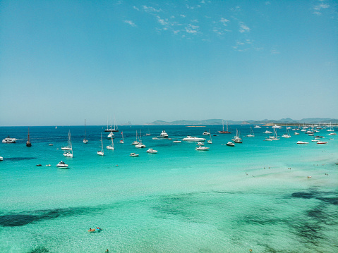 Ses Illetes Beach in Formentera, right next to Ibiza. With Mediterranean turquois waters and sailing yatch and boats.