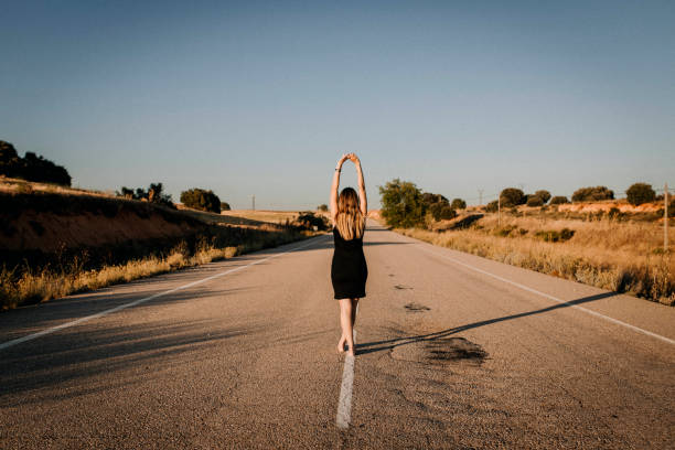 Una donna con un vestito nero su una strada vuota - foto stock