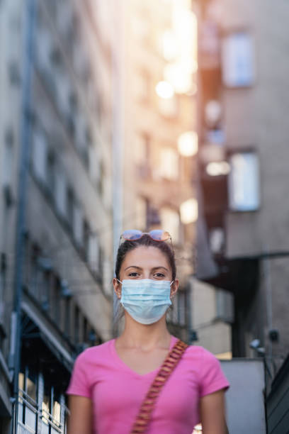 junge frau mit gesichtsmaske in der stadt - fine art portrait portrait street looking at camera stock-fotos und bilder