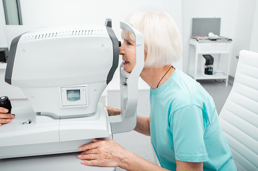 Elderly woman checking eyesight in a clinic using diagnostic ophthalmic equipment. Patient checking vision, ophthalmology modern technology