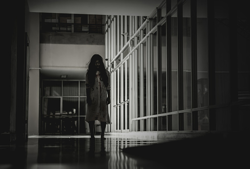 Woman in ghost or zombie on halloween festival at dark place, standing in the hallway and looking at you. Horror or halloween festival concept.