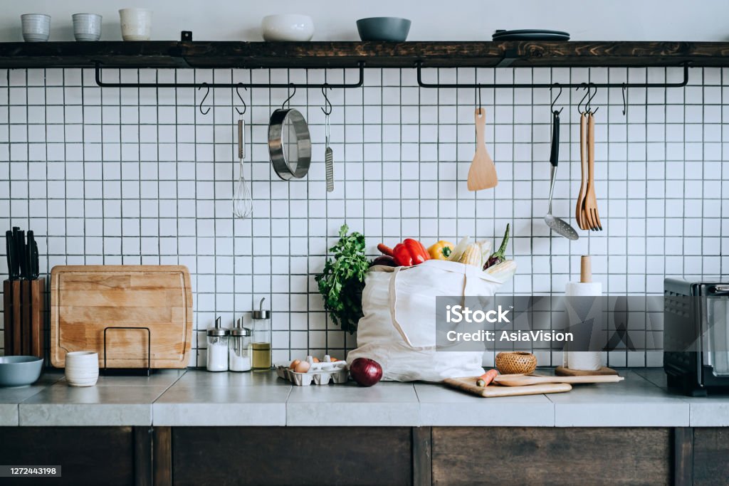 A reusable bag full of colourful and fresh organic vegetables and groceries on the kitchen counter. Zero waste shopping and sustainable lifestyle concept Cooking Stock Photo