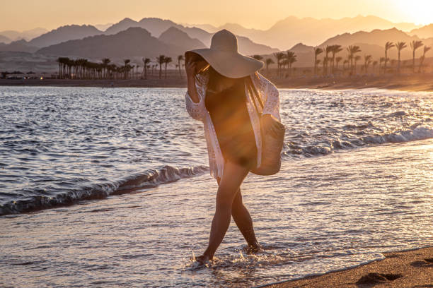 istock Woman at sunset on the beach in a hat. 1272443366