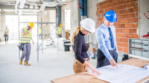 istock Businessman and architect examining plans on a construction site 1272443489