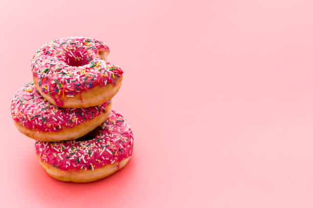 istock Pink berry donuts close up. Glazed and sprinkles bakery 1272444796