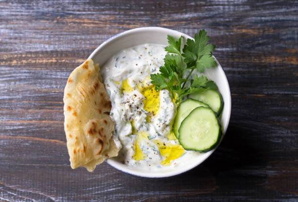 Traditional greek yogurt tzatziki sauce with cucumbers and herbs on wooden background Traditional greek yogurt tzatziki sauce with cucumbers and herbs on wooden background, top view, space tzatziki stock pictures, royalty-free photos & images