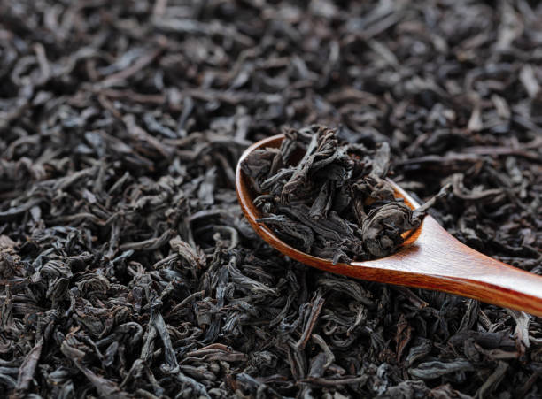 istock black tea leaves with wooden spoon on a tea background 1272448771