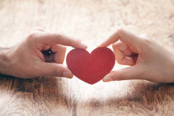 istock Male and female hands holding red heart. 1272449864