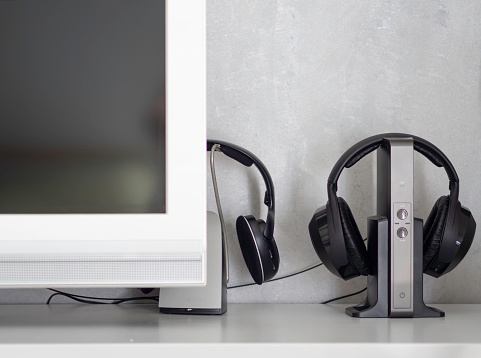 Wireless noise-canceling black headphones charging next to television for watching tv or listen to music at home.