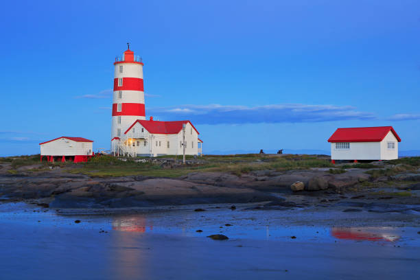 Pointe-des-Monts Lighthouse at dusk with reflections in the sea, Cote-Nord, Quebec Pointe-des-Monts Lighthouse at dusk with reflections in the sea, Cote-Nord, Quebec, Canada cote nord photos stock pictures, royalty-free photos & images