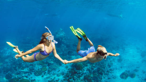 シュノーケリングマスクの若いカップルは、海の水中で自由にダイビング - nusa lembongan bali island beach ストックフォトと�画像