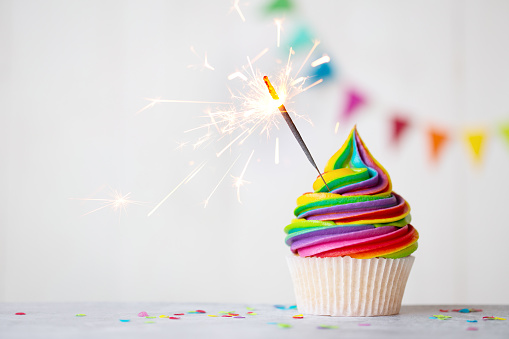 Colorful rainbow cupcake with celebration sparkler