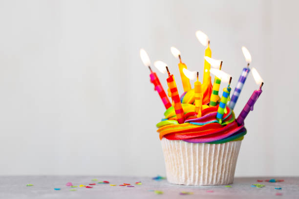 istock Birthday cupcake with rainbow frosting and candles 1272454537