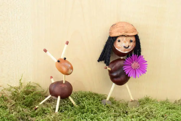 Smiling girl and cute animal - figurines made of chestnuts and acorns