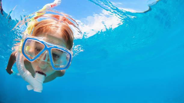 Child in snorkeling mask dive underwater in blue sea lagoon Happy little kid in snorkeling mask and wetsuit jump and dive underwater in coral reef sea lagoon. Family travel lifestyle in summer adventure camp. Swimming activities on beach vacation with child. summer camp photos stock pictures, royalty-free photos & images