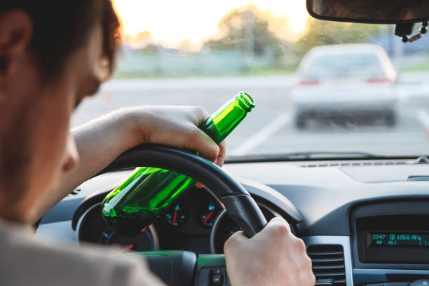 A man driving a car with a bottle of beer Drunk young man driving a car with a bottle of beer. Don't drink and drive concept. Driving under the influence. DUI, Driving while intoxicated. DWI driving under the influence stock pictures, royalty-free photos & images