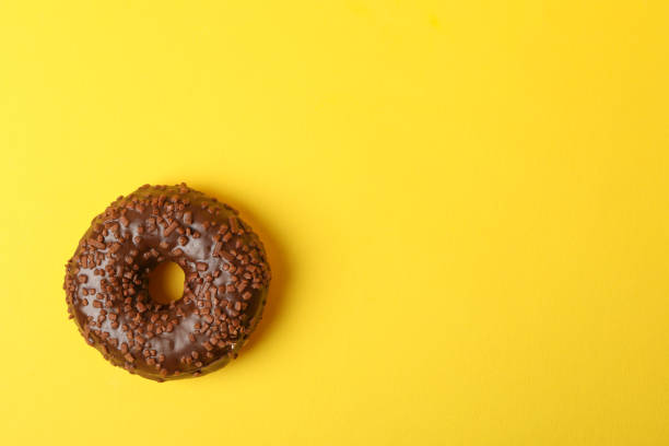 istock Tasty chocolate donut on yellow background, space for text 1272456196