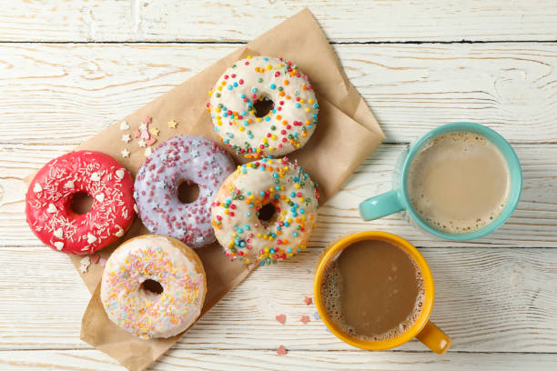 istock Coffee and tasty donuts on wooden background, top view 1272457143