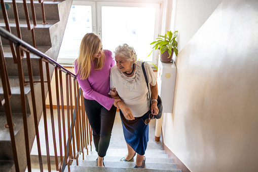 Cuidador ayuda a la mujer mayor a subir escalera photo