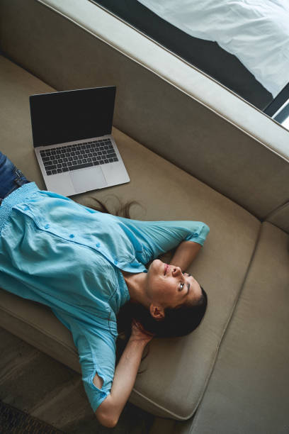 istock Serene young woman daydreaming on the sofa 1272458678