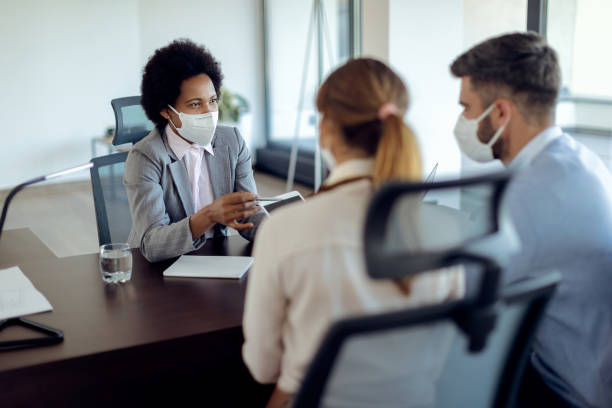 istock Black financial advisor and her clients using touchpad while wearing protective face masks on a meeting. 1272458761